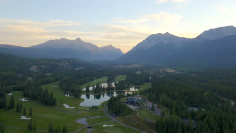 Drone-aerial-view-of-green-golf-course-in-the-rocky-mountains-of-Banff-and-Kananaskis-of-Alberta,-Canada-in-morning