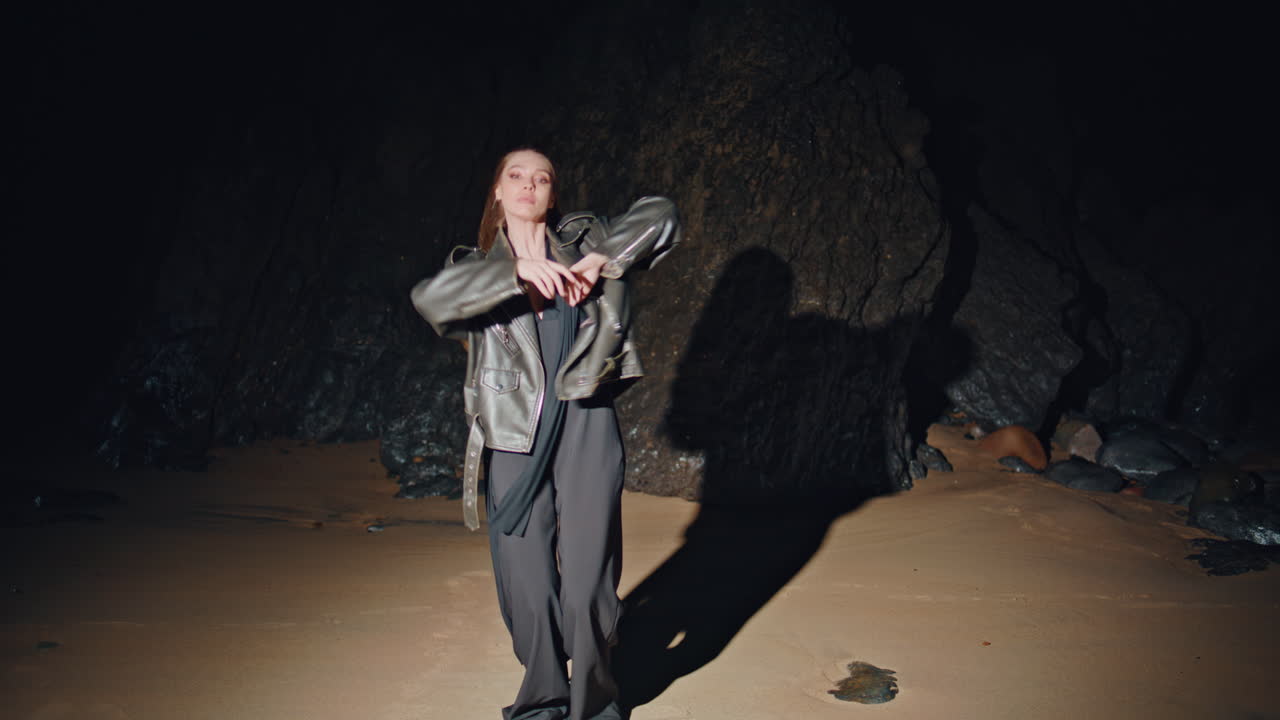 Dançarina contemporânea gesticulando, apresentando-se na praia de areia ao entardecer. Mulher em festa.