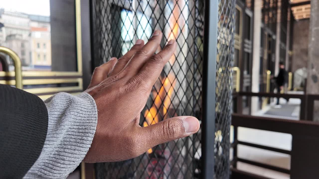 Person warming their hand near a modern fireplace
