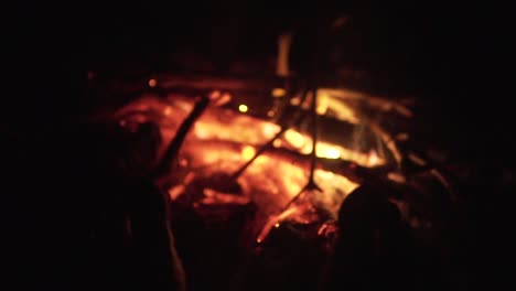 man's legs against the bonfire embers in the forest