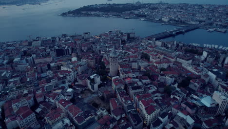 Galata-tower,-the-city-of-Istanbul-and-a-big-river-on-a-gloomy-day-with-clouds,-aerial-view-and-drone-shot,-slow-motion