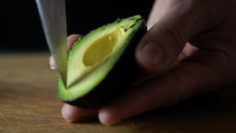 slicing through green avocado with tip of sharp chefs knife, slow motion