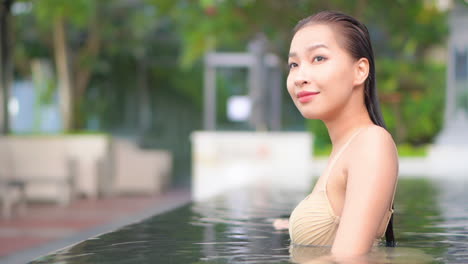 a close-up of a woman in a swimming pool turns her head to look at the camera