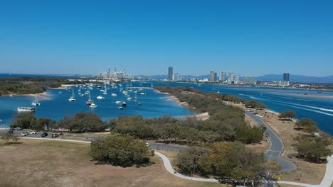 Vista-Aérea-De-Un-Día-Ajetreado-En-Una-Vía-Fluvial-Popular-Con-El-Horizonte-De-La-Ciudad-A-Lo-Lejos