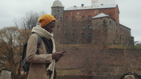 black male tourist walking in old town and using phone