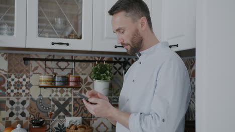 man using a phone in the kitchen