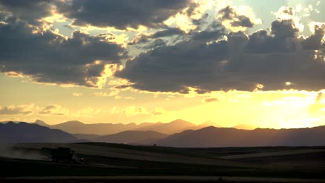 Cosechadora-En-La-Zona-Rural-De-Colorado,-En-Un-Contexto-De-Montañas-Y-Puesta-De-Sol