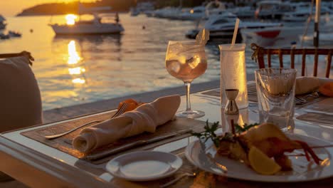 romantic sunset dinner featuring exquisite seafood and refreshing cocktails, elegantly arranged on a table in a luxury restaurant by the sea, creating an idyllic and unforgettable atmosphere