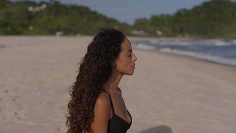 una mujer joven meditando en la playa.