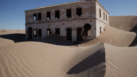 abandoned building swallowed by sand dunes in kolmanskop ghost town