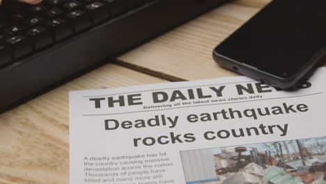 newspaper headline featuring devastation caused by earthquake disaster on desk next to computer keyboard and phone 3