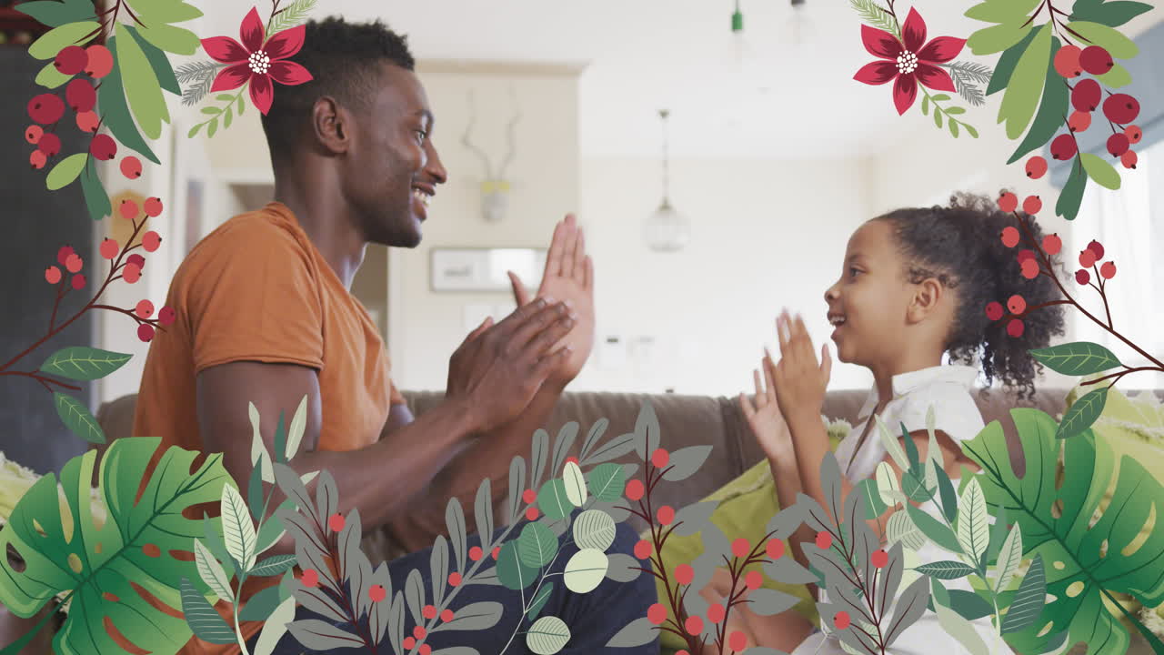 animación de flores sobre un feliz padre y hija afroamericanos jugando en el sofá