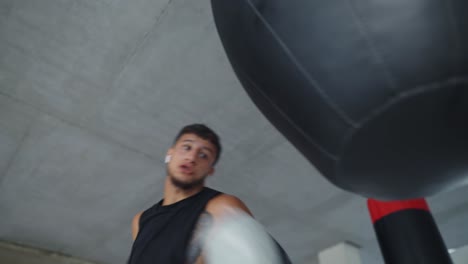 low angle view male boxer training aggressively with boxing bag