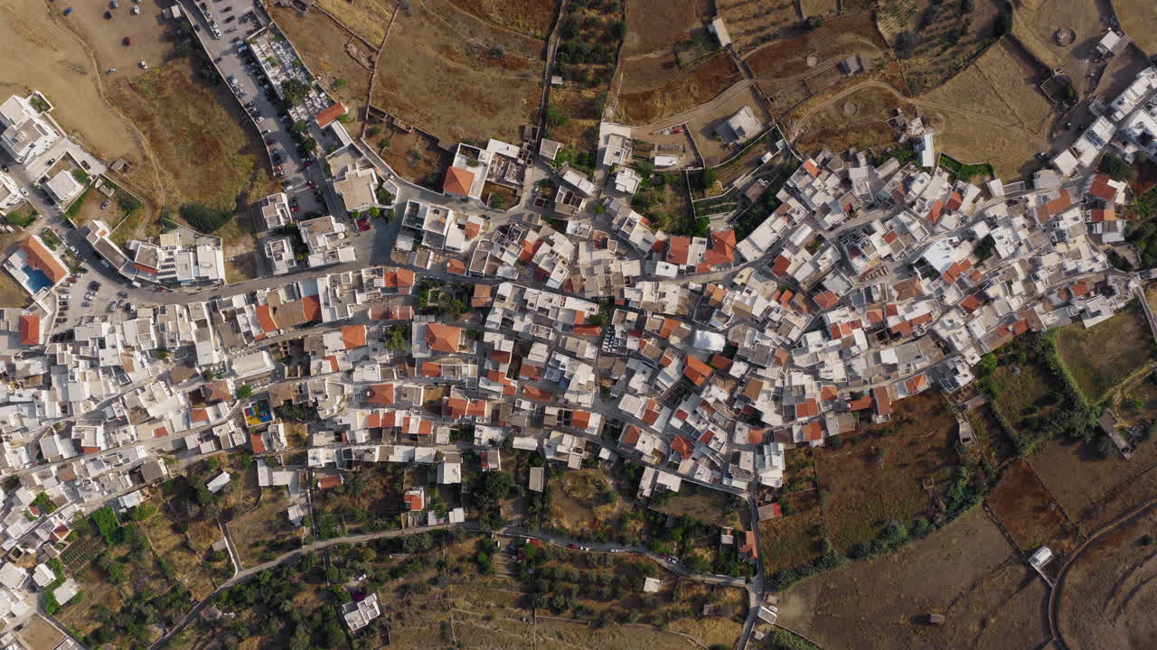 Top-down drone footage of Kythnos Chora at sunrise. Warm sunlight reveals the structure and symmetry of this traditional Greek island village