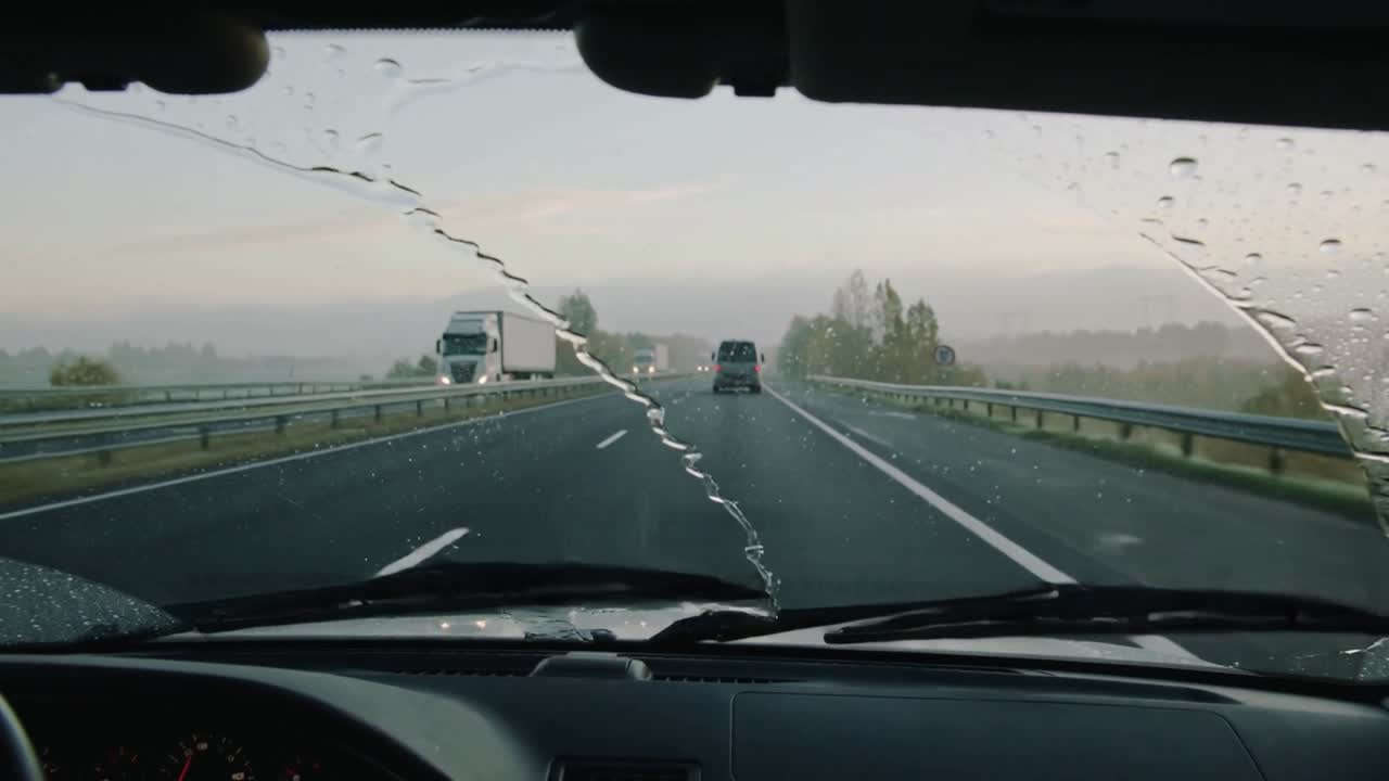 In risposta a una pioggia leggera, i tergicristalli spazzano il parabrezza sull'autostrada al mattino, liberando la visuale.