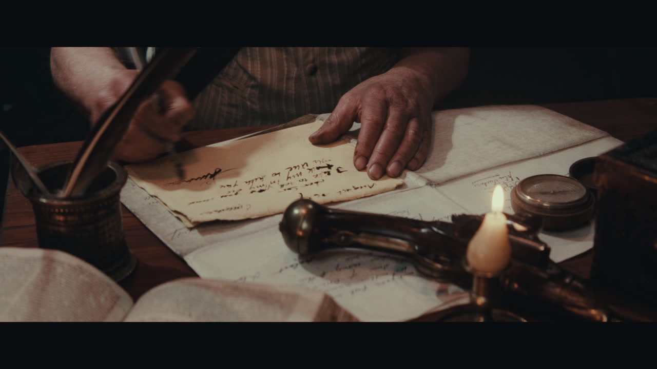 An old captain sits writes a letter inside the sailing ship cabin