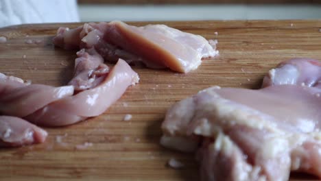 cortar la carne de pechuga de pollo en una tabla de cortar de madera con un cuchillo de cocina