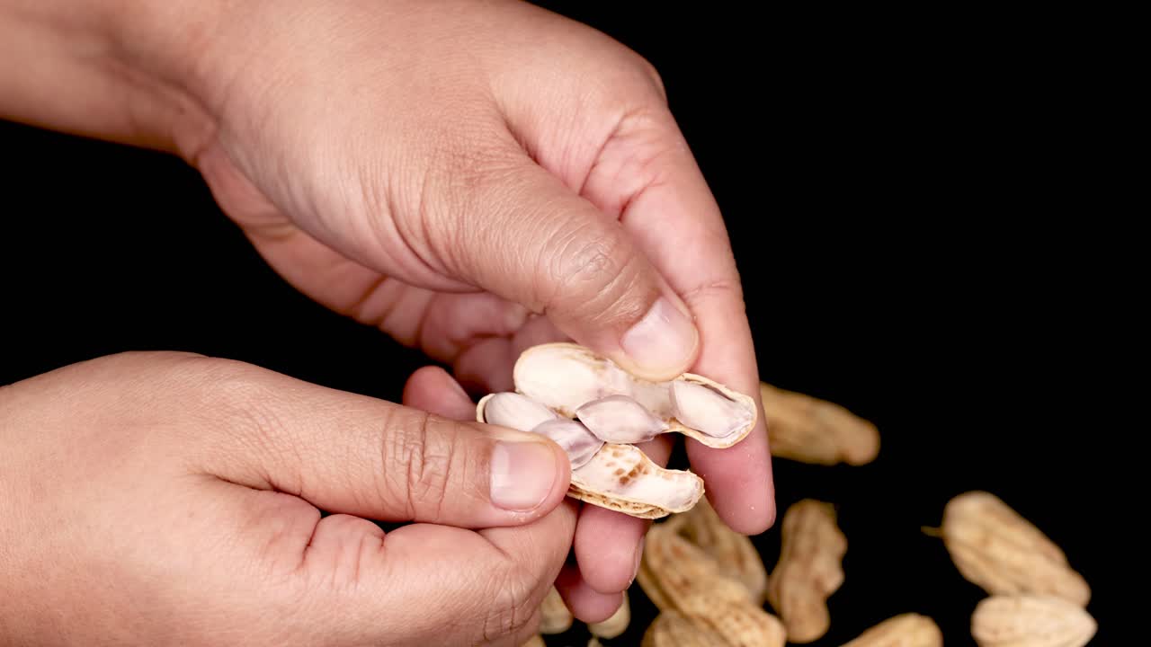 검은색 배경 위에서 땅콩을 는 손