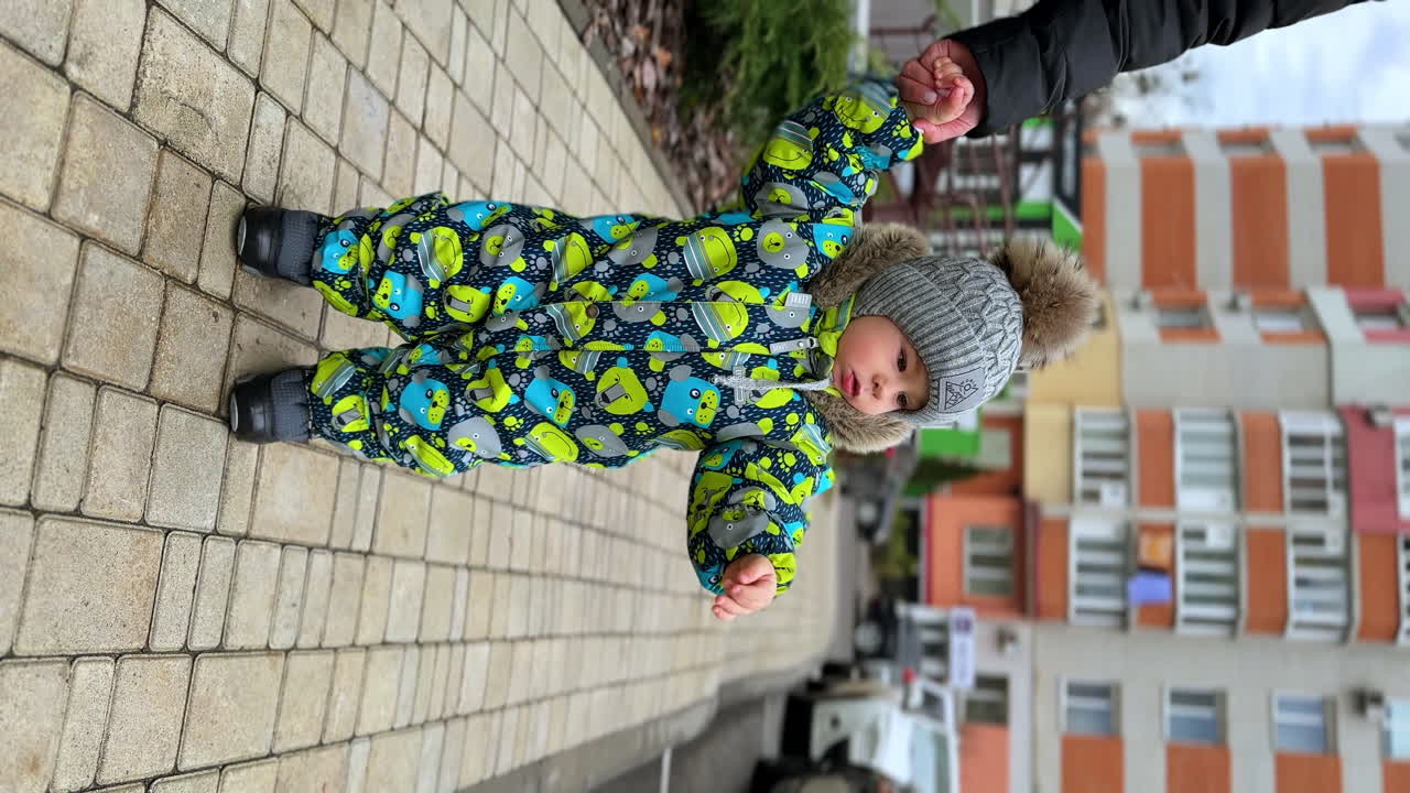 Baby learning to walk outdoors in winter clothes