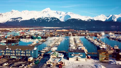 4k drone video of seward boat harbor and surrounding snow covered mountains on snowy winter day in alaska