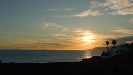puesta de sol sobre el océano con casas y palmeras