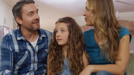 Parents-talking-with-their-daughter-on-couch