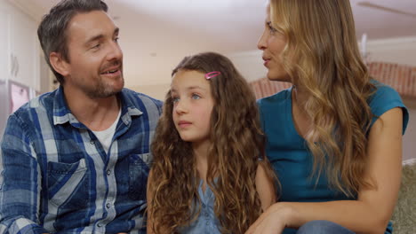 padres hablando con su hija en el sofá