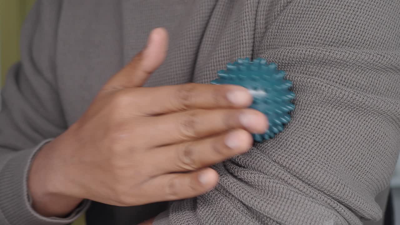 Person som masserar sin arm med en taggig massageboll
