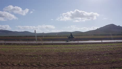 motorcycle rider moving on empty road in rural countryside, parallel tracking shot