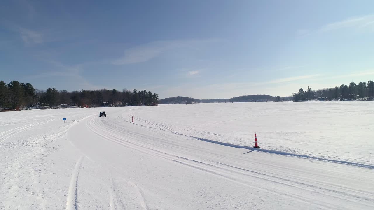 En specialbygget UTV racer i høj fart rundt på en snedækket bane på en solrig dag.