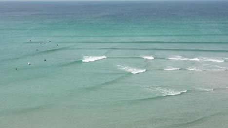 Ocean-Waves-Crossing-Over-Each-Other-Along-a-Beach-in-Cornwall-with-Surfers