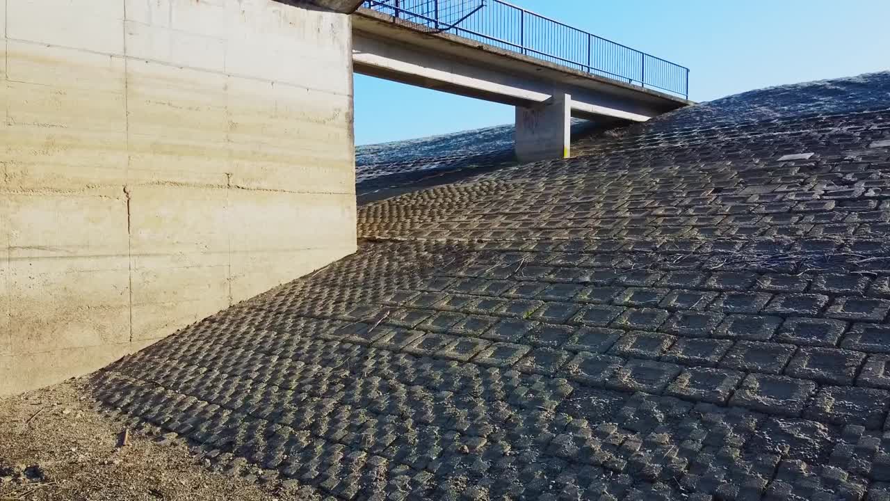 Aerial shot flying towards a retaining wall in dry Zovnek lake, Slovenia