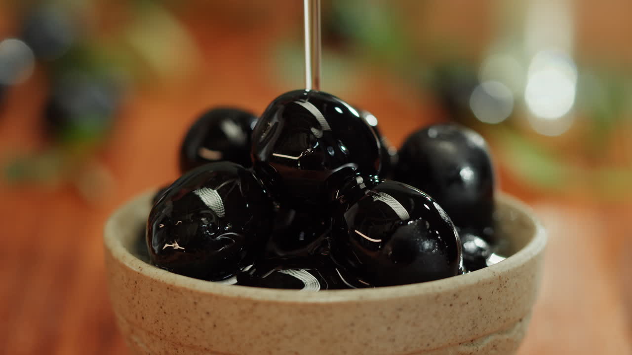 Pouring Olive Oil over Black Olives