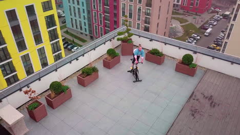 healthy caucasian woman exercising workout on stationary cycling machine bike on house rooftop gym