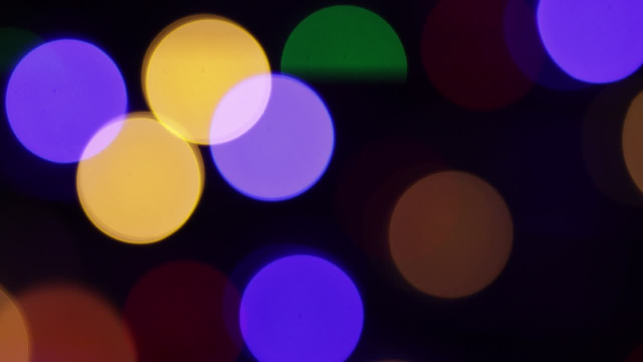 Christmas blur background. Shimmering colored circles defocused christmas lights video. Multicolored light leaks 4k footage on black background