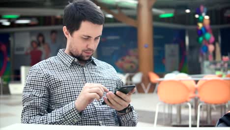 hombre usando un teléfono inteligente en un patio de comidas