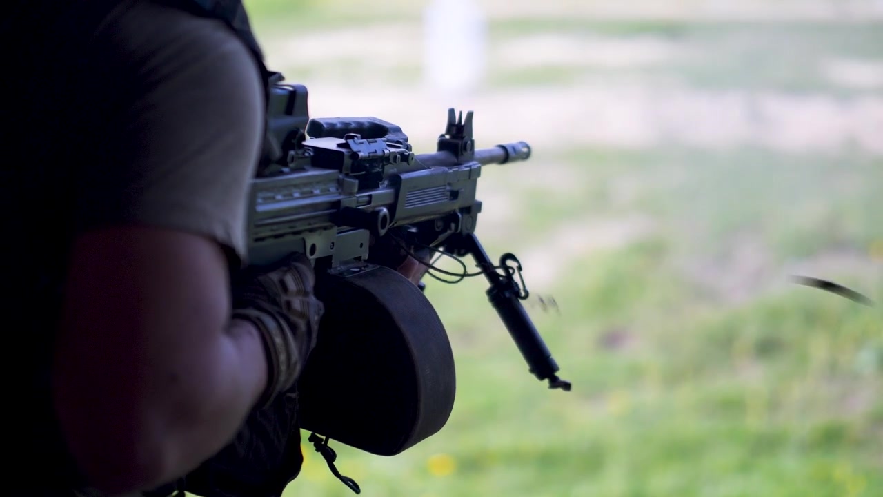 Israeli army soldier fires machine gun with visible shell ejection outdoors
