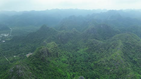 aerial pan right showing rugged terrain covered in lush green forest on a cloudy day in cat ba island