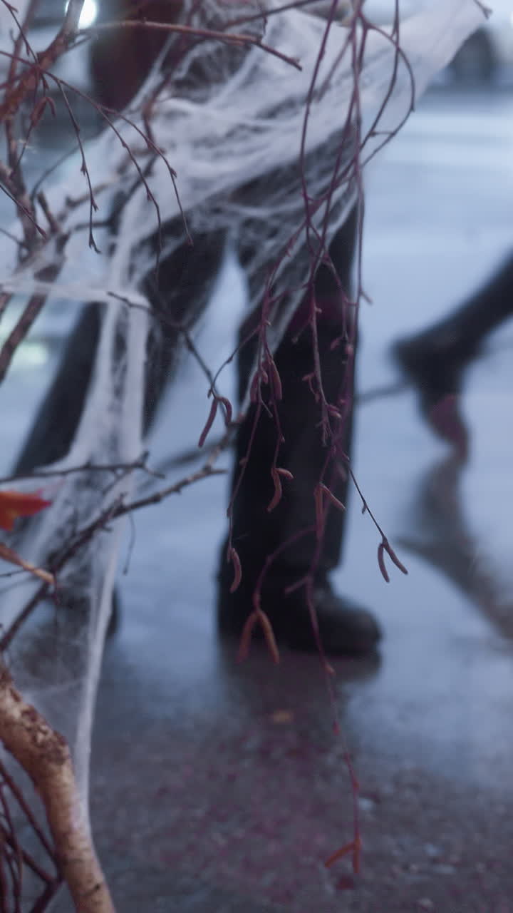 Close-up of person in black trousers and boots walking calmly on wet ground during rainy weather, with a focus on legs, reflecting the rainy mood and wet pavement around them