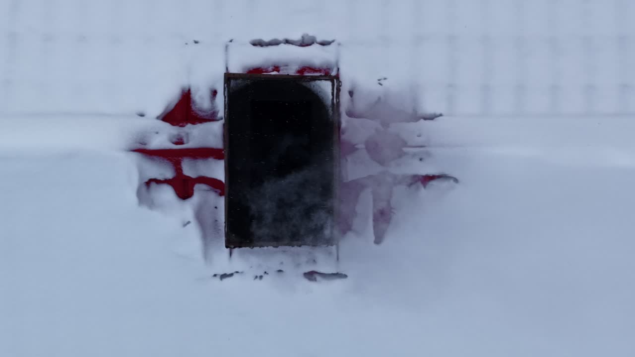 A building completely covered in snow behind a steaming hot panel