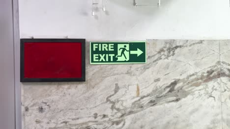 static shot of Fire Exit Sign and a notice board placed on the wall to guide people in case of emergency