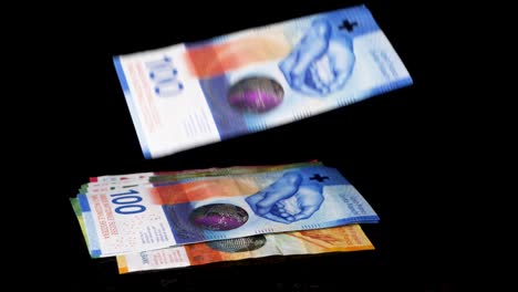 swiss franc bills are slowly raining down from above forming a pile against a black background