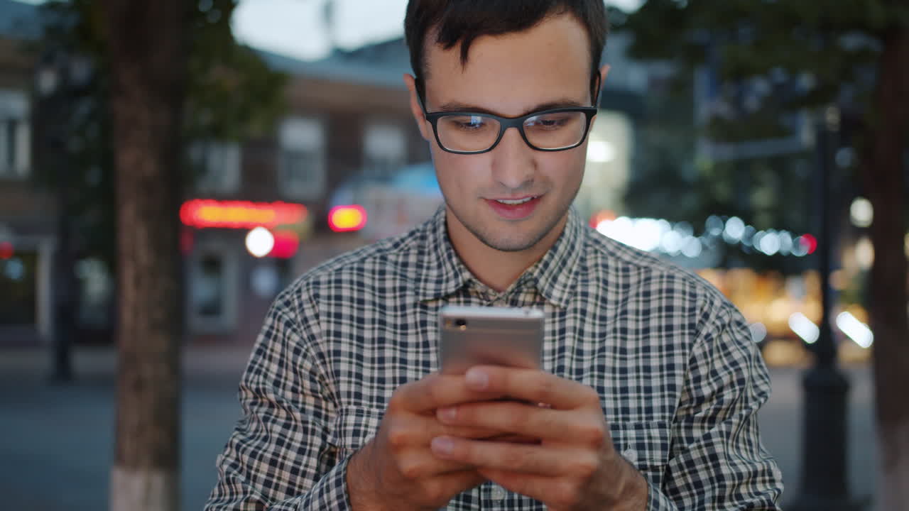 Hombre Usando un Smartphone de Noche en una Ciudad