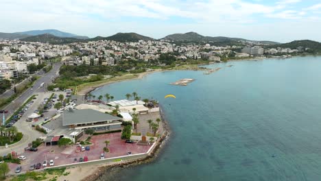 Aerial-view-of-Powered-Paragliding-flyover-scenic-beach-coastline-in-Glyfada