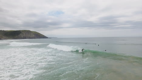 Cinematic flying of surfers surfing along coast of East London South Africa aerial
