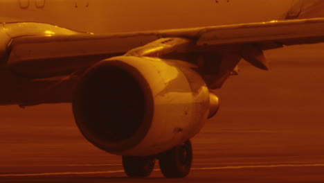 close up of engine under the wing of airplane passenger jet on runway airstrip in slow motion