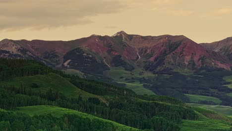 Aerial-over-green-forested-hills-near-the-Crested-Butte-mountain,-Colorado,-USA