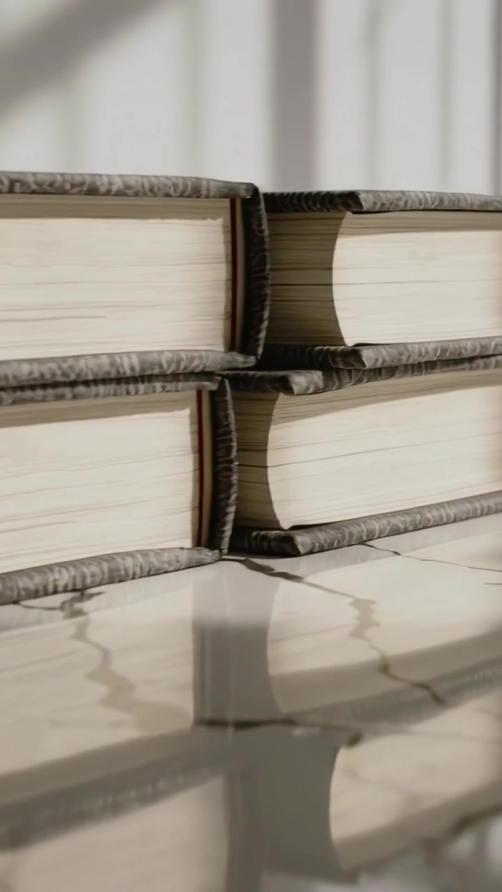 Video verticale: Telecamera che effettua una panoramica mostrando quattro libri su una pietra vicino a una finestra, con le persiane che creano riflessi a strisce.