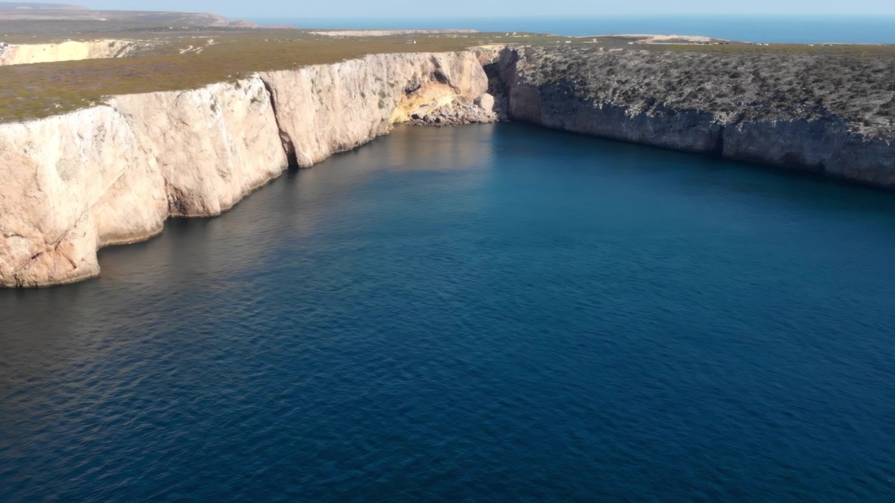 Cala calcarea aerea, bacino turchese, acque calme, ispettore costiero che monitora il litorale con drone, bianco