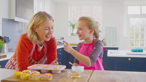 grandmother with granddaughter having fun decorating homemade cakes on kitchen counter at home